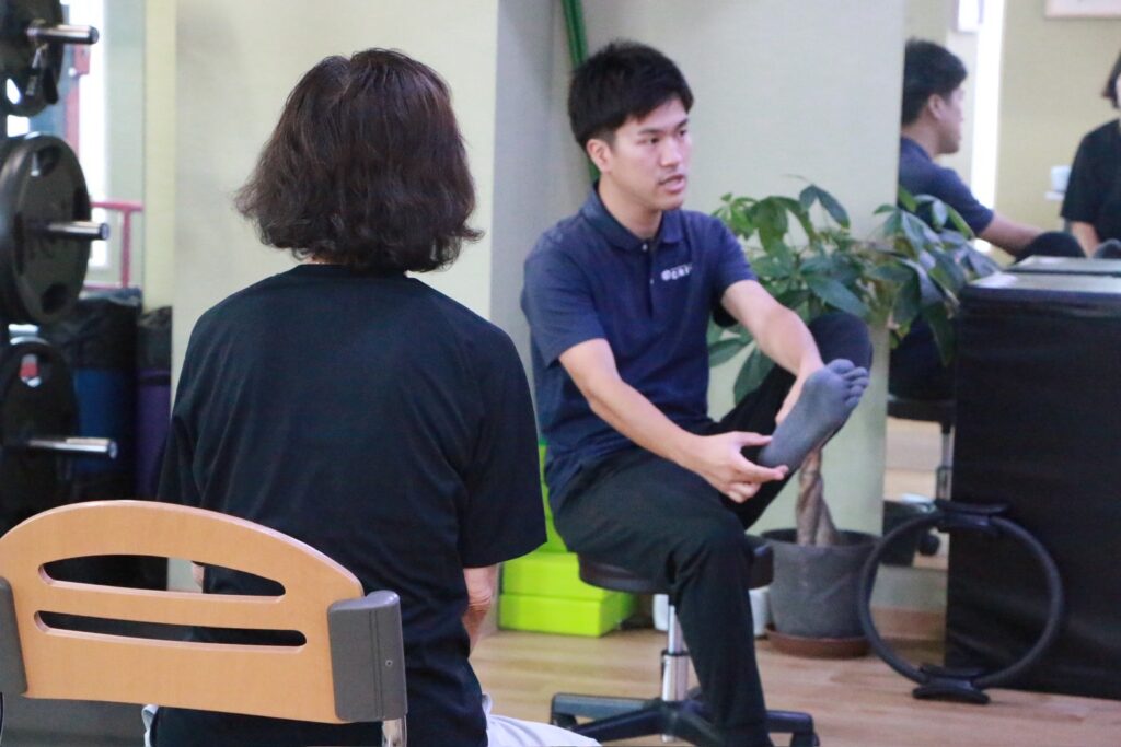 理学療法士が椅子に座った状態でセルフケアや動作指導を行う様子｜金沢区 整体
