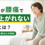 高齢女性がベッドから起き上がる際に腰を押さえている様子｜高齢者が腰痛で起き上がれない原因を理学療法士が解説